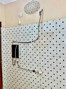 a shower in a bathroom with black and white tiles at The cape vills in Kampala