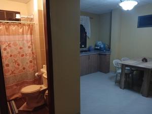 a bathroom with a toilet and a kitchen with a table at Suites Sonikikos in Ballenita