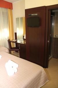 a hotel room with two beds and a desk and a television at Villa Adriana Hotel in Tivoli