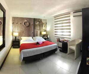 1 dormitorio con 1 cama grande con manta roja en Hotel Puerta de San Antonio, en Cali