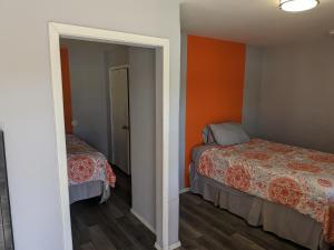 1 dormitorio con 2 camas y pared de color naranja en El Rey Motel, en Globe