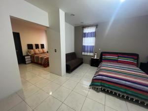 ein Schlafzimmer mit einem Bett und einem Sofa in einem Zimmer in der Unterkunft Alojamientos OHANA in Oaxaca de Juárez