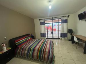 Schlafzimmer mit einem Bett, einem Schreibtisch und einem Fenster in der Unterkunft Alojamientos OHANA in Oaxaca de Juárez