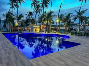 a swimming pool with palm trees and blue lighting at Isla Beach Hotel in Pecém