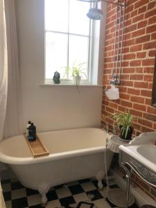 a white bath tub in a bathroom with a brick wall at Lovely room in period townhouse in Winchester