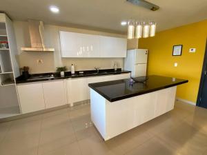 a kitchen with white cabinets and a black counter top at Departamento con vista al mar in Mazatlán +16 photos