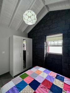 ein Schlafzimmer mit einer bunten Decke auf einem Bett in der Unterkunft Cantinho dos Cagarros in Lajes do Pico