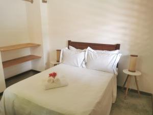 a bedroom with a white bed with two flowers on it at Le Jardin d'Éole - Pousada em Pontal de Maceio in Fortim