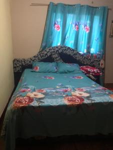 Una cama con un edredón azul con flores. en HOSPEDAJE PRÓCERES DE MAYO, en Encarnación
