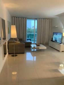 uma sala de estar com um sofá e uma televisão em Lovely Beach Apartment by Miami Te Espera- HOLLYWOOD 5U em Hollywood