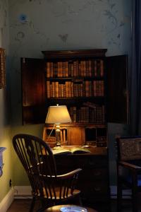 einen Schreibtisch mit einer Lampe und ein Bücherregal mit Büchern in der Unterkunft Château de La Tour en Brenne in Rivarennes