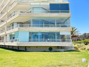 an apartment building with large glass balconies and a lawn at Departamento San Alfonso del Mar, primer piso in Algarrobo