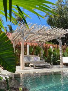 a wooden pergola with a bench next to a pool at Lost Paradise Gili in Gili Trawangan