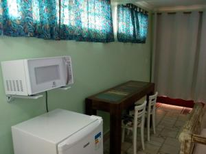 a kitchen with a microwave and a table with chairs at Suite Ilhabela in Ilhabela