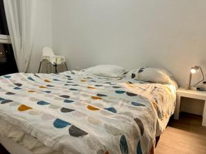 uma cama com um edredão colorido num quarto em T3 65 m2 avec parking 15 mns Paris by immo kit bnb em Gagny