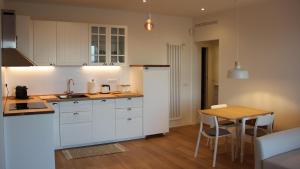 a kitchen with white cabinets and a wooden table at Mari'Entu in Quartu SantʼElena