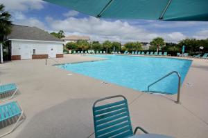 a swimming pool with blue chairs in a resort at Palmy Days @ Ironwood 424 in Myrtle Beach