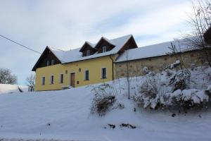 uma casa amarela com neve em cima em Penzion Za plotem 