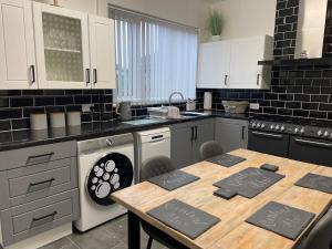 a kitchen with a table and a sink and a dishwasher at Central Blue Holiday Home. in Bridlington