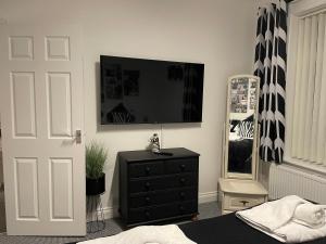 a bedroom with a black dresser and a flat screen tv at Central Blue Holiday Home. in Bridlington