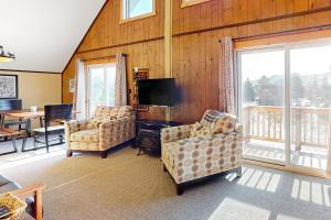 a living room with two chairs and a flat screen tv at Alpine Horn Lodge at Big Powderhorn Mountain in Ironwood