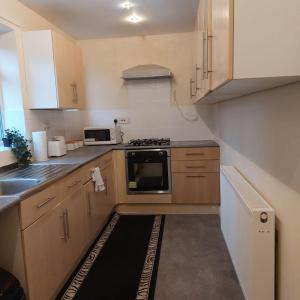 cocina pequeña con armarios de madera y fogones en Three Bed House with free on-site parking Sleeps 5 en Warrington