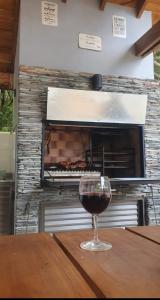 ein Glas Wein auf einem Tisch vor einem Ofen in der Unterkunft Cabañas LOS BEDUINOS in Mar de las Pampas