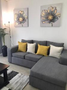 een woonkamer met een grijze bank en gele kussens bij Modern Exec 2Bed Apartment at Infinite in Johannesburg
