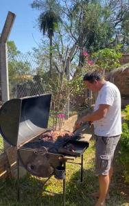 un hombre está cocinando comida en una parrilla en La Casita de Aregua, en Itauguá