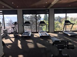 een fitnessruimte met diverse loopbanden in een kamer met ramen bij Modern Exec 2Bed Apartment at Infinite in Johannesburg