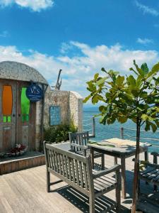 a table and benches on a deck with the ocean at VnS Beachfront Guesthouse in Nusa Penida +21 photos