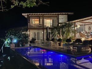 una casa con piscina por la noche en Villa das Graças, en Ilhabela