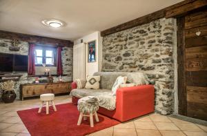a living room with a red chair and a stone wall at Maison Chasseur Alpine Design Lodge in Champoluc