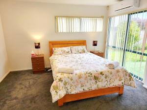 ein Schlafzimmer mit einem Bett und einem großen Fenster in der Unterkunft Incredible Waitakere View in Auckland