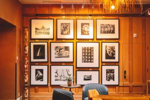 a wall of pictures on a wall with chairs at Hotel Lucia in Portland