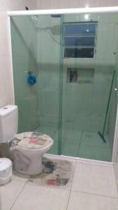 a bathroom with a toilet and a glass shower at Casa bom espaço para passar suas férias in Matinhos