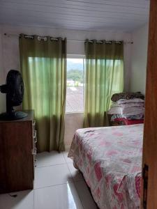 sypialnia z łóżkiem i oknem z zielonymi zasłonami w obiekcie Casa bom espaço para passar suas férias w mieście Matinhos