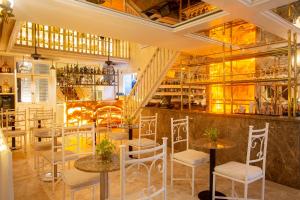 un restaurante con sillas blancas, mesas y escaleras en Leones de Alba Hotel Boutique, en Cartagena de Indias