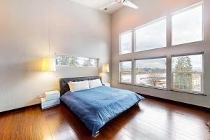 a bedroom with a bed with blue sheets and windows at Spokane River Retreat in Coeur d'Alene