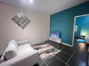 sala de estar con sofá blanco y pared azul en Sermie T2 climatisé avec piscine en Kourou