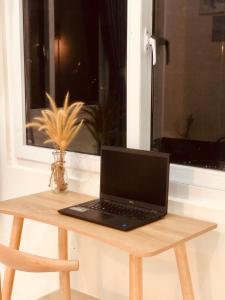 laptopa siedzącego na drewnianym stole przed oknem w obiekcie Stella's Home w Duong Dong