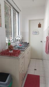 eine weiße Küche mit Spüle und Fenster in der Unterkunft Dihome Ariel Studio in Donggongon