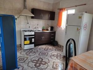 a kitchen with a white refrigerator and a stove at Complejo de Cabañas Las Mellizas in San Agustín de Valle Fértil