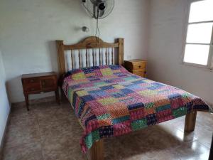 ein Schlafzimmer mit einem Bett mit einer bunten Decke in der Unterkunft Complejo de Cabañas Las Mellizas in San Agustín de Valle Fértil