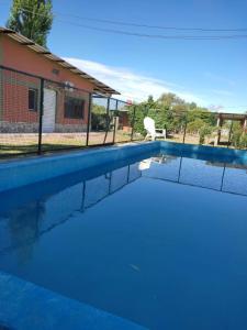 una piscina con una silla junto a una casa en Complejo de Cabañas Las Mellizas en San Agustín de Valle Fértil