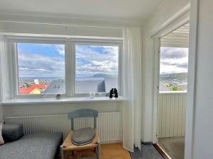 een kamer met 2 ramen en een stoel en een bed bij Apartment in Torshavn in Tórshavn