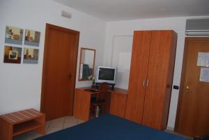 Schlafzimmer mit einem Schreibtisch, einem TV und Holzschränken in der Unterkunft Telma Hotel in Terracina