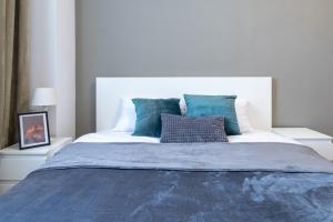 una camera da letto con un grande letto con lenzuola e cuscini blu di Old Town's Legend: City center condo with balcony a Maribor