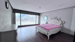 um quarto com uma cama branca e um cobertor rosa em Yesan Sarang Pension em Hongseong