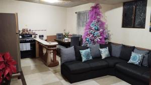 Sala de estar con sofá negro y árbol de Navidad en Departamento Céntrico y cerca del Foro Sol en Ciudad de México